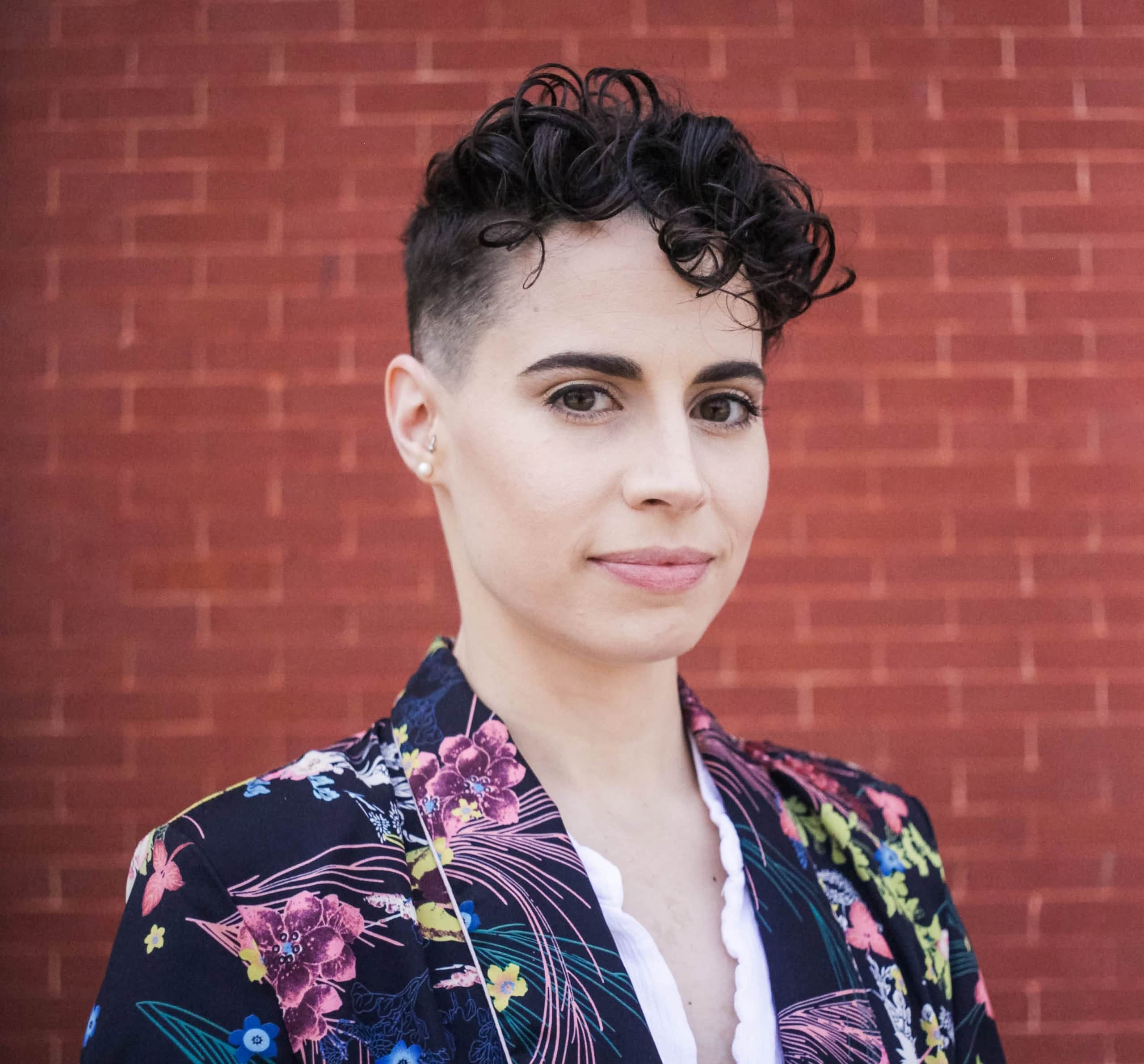 A woman with curly hair wearing a floral jacket